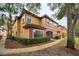 Two-story condo building with a yellow and red exterior and lush landscaping at 2254 Chianti Pl # 68, Palm Harbor, FL 34683