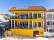 Bright yellow beachfront home featuring private balconies with black railings and a red tile roof at 3702 El Centro St, St Pete Beach, FL 33706