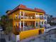 Stunning three-story yellow home on a beach with balconies and orange tile roof at 3702 El Centro St, St Pete Beach, FL 33706