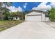 White house with attached garage and a spacious driveway, surrounded by lush greenery at 3915 Briarlake Dr, Valrico, FL 33596