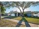 Charming single-story home with stone accents, a well-manicured lawn, and a mature tree providing shade at 435 Laughing Gull Ln, Palm Harbor, FL 34683