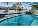 Screened-in pool with crystal-clear water, brick trim, lounge seating, and a pool cleaning robot at 435 Laughing Gull Ln, Palm Harbor, FL 34683