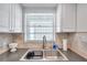 Clean kitchen featuring a double sink, modern faucet, and stone backsplash at 4455 Duhme Rd # 305, St Petersburg, FL 33708