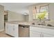 Efficient kitchen with a stainless steel dishwasher, white cabinetry, and a window overlooking the backyard at 5205 Landsman Ave, Tampa, FL 33625