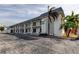 Exterior view of Sunset Plaza, a light-colored building with balconies and palm trees at 680 71St Ave # 14, St Pete Beach, FL 33706