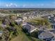 Aerial view of townhomes with a large grassy area and mature trees with a glimpse of a golf course in the distance at 6972 Ripple Pond Loop, Zephyrhills, FL 33541