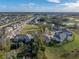 Aerial view of townhomes with a large grassy area, mature trees and a glimpse of a pond in the distance at 6972 Ripple Pond Loop, Zephyrhills, FL 33541