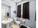 Bright bathroom with a pedestal sink, toilet and a window covered with a black curtain at 6972 Ripple Pond Loop, Zephyrhills, FL 33541