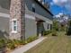 Exterior view of a two-story townhome featuring stone accents and a well-maintained lawn at 6972 Ripple Pond Loop, Zephyrhills, FL 33541