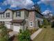 Inviting townhome featuring a stone accent wall, attached garage, and lush landscaping, perfect for comfortable living at 6972 Ripple Pond Loop, Zephyrhills, FL 33541