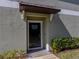 Close-up of a townhome's front door with a dark brown awning and manicured landscaping at 6972 Ripple Pond Loop, Zephyrhills, FL 33541