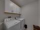 Functional laundry room featuring a white washer, dryer, and upper cabinets for ample storage space at 6972 Ripple Pond Loop, Zephyrhills, FL 33541