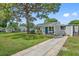 Gray house with blue door, driveway, and mature tree at 7234 12Th N St, St Petersburg, FL 33702