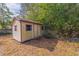 Beige storage shed nestled in a backyard with lush landscaping at 1454 Brigadier Dr, Spring Hill, FL 34608