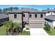 Two-story house with gray siding, a three-car garage, and palm trees at 14834 Paddock Pond Ave, Lithia, FL 33547