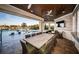 Covered outdoor dining area with pool view, seating for eight, and a large flat-screen TV at 335 Bath Club S Blvd, North Redington Beach, FL 33708