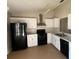 Galley kitchen with white cabinets and black appliances at 6802 Seaview Way, Tampa, FL 33615