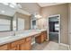 Bathroom with double sinks, a large mirror, and a view of the bedroom at 6944 Runner Oak Dr, Wesley Chapel, FL 33545