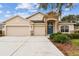 House exterior featuring a three-car garage and stone accents at 6944 Runner Oak Dr, Wesley Chapel, FL 33545