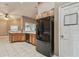 Kitchen features black refrigerator, wood cabinets, and tile floor at 6944 Runner Oak Dr, Wesley Chapel, FL 33545