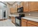 View of kitchen with black appliances and wood cabinets at 6944 Runner Oak Dr, Wesley Chapel, FL 33545