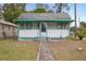 Charming bungalow with a white exterior, green trim, and a walkway at 710 Seminole St, Clearwater, FL 33755