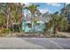 Charming light blue beach cottage with palm trees and white awnings at 128 Bay Plz, Treasure Island, FL 33706