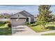 One-story home with gray siding, two-car garage, and landscaped lawn at 19724 Post Island Loop, Land O Lakes, FL 34638