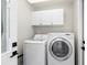 Bright laundry room with washer, dryer, and overhead cabinets at 6518 Senegal Palm Way, Apollo Beach, FL 33572
