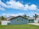 Side view of a well-maintained, light blue single-story home with a green lawn and a white privacy fence at 1004 Peninsula Ave, Tarpon Springs, FL 34689