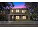 Two-story house with front porch, stone accents, and white picket fence at dusk at 10515 Fenceline Rd, New Port Richey, FL 34655