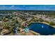 Aerial view of community with lake, pool, and lush landscaping at 1882 Pine Ridge W Way # E1, Palm Harbor, FL 34684