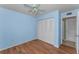 Light blue bedroom with wood-look tile flooring and double-door closet at 1882 Pine Ridge W Way # E1, Palm Harbor, FL 34684