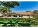 Rear view of single-story home with landscaped yard at 1882 Pine Ridge W Way # E1, Palm Harbor, FL 34684