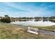 Serene lake view with walkway and white bench at 1882 Pine Ridge W Way # E1, Palm Harbor, FL 34684