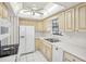 Galley kitchen with white appliances and light wood cabinets at 2300 Lancaster Dr, Clearwater, FL 33764