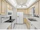 Galley kitchen with white appliances and light wood cabinets at 2300 Lancaster Dr, Clearwater, FL 33764