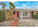 Red door entry to brick ranch house with landscaping at 5290 38Th S Way, St Petersburg, FL 33711