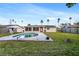 A lush backyard with a freeform pool, patio, lush lawn, and trees complements the house with its enclosed sunroom at 5600 Bayou Grande Ne Blvd, St Petersburg, FL 33703