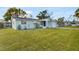 Single-story home with a green lawn, an attached garage, and mature trees in the background at 5600 Bayou Grande Ne Blvd, St Petersburg, FL 33703