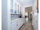 White butler's pantry with quartz countertops and glass-front cabinets at 7853 Roma Dune Dr, Wesley Chapel, FL 33545