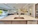 Kitchen island with large sink, white countertop, and a view into the Gathering and living area at 5612 Limelight Dr, Apollo Beach, FL 33572