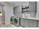 Modern laundry room with gray cabinets, quartz countertop, and a utility sink at 5612 Limelight Dr, Apollo Beach, FL 33572