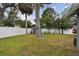 Large backyard featuring a white fence, mature shade trees and palms, and plenty of space for relaxing or entertaining at 12840 Sophia Cir, Largo, FL 33774