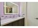 Bathroom vanity featuring a sink and dark wood cabinetry, marble look tile walls, and a backlit mirror at 12840 Sophia Cir, Largo, FL 33774