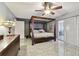 Stylish bedroom with dark wood four-poster bed frame, gray walls, tile flooring, and modern decor at 12840 Sophia Cir, Largo, FL 33774