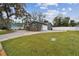 Exterior view of the home showcasing the garage, spacious yard, landscaping, and a glimpse of the backyard fence at 12840 Sophia Cir, Largo, FL 33774