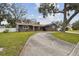 Beautiful front exterior showcasing a well-maintained lawn, circular driveway, and mature trees shading the home at 12840 Sophia Cir, Largo, FL 33774