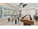 The game room offers a foosball and shuffleboard table with ample natural light from large windows and a ceiling fan at 12840 Sophia Cir, Largo, FL 33774
