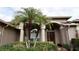 A closer view of the front entrance with palm trees and decorative plants enhancing the curb appeal at 29120 Rivergate Run, Wesley Chapel, FL 33543